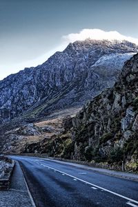 Road by mountains against sky