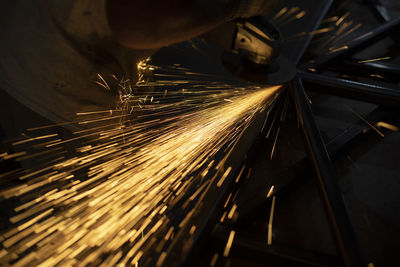 Sparks from steel. metal sawing. lights in dark. work in garage. sawing workpiece.