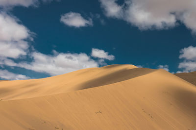 Sand dunes in desert against sky