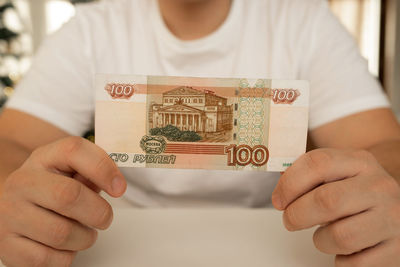 A close-up man holds in his hands an unfolded bill with a face value of 100 rubles