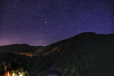 Scenic view of silhouette mountains against star field at night