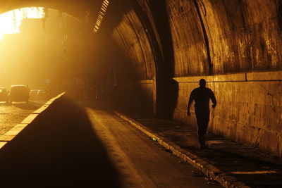Rear view of silhouette man standing in tunnel