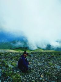 Full length of boy sitting on land against sky