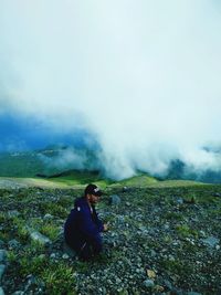 Woman sitting on land against sky