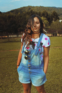 Portrait of young woman standing on field against sky