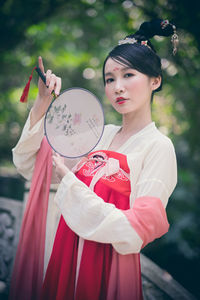Young woman holding umbrella standing outdoors