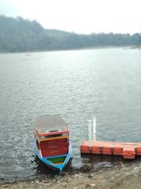 Boat moored in lake against sky