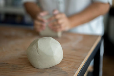 Midsection of woman kneading clay on table in workshop