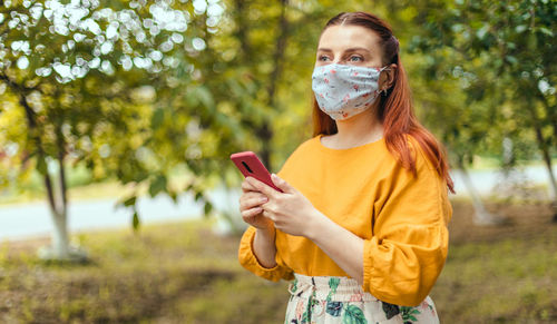 Young woman drinking water while standing outdoors