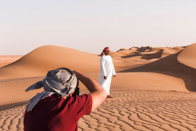 Senior man taking pictures of a bedouin, wahiba sands oman