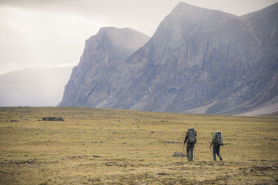 Rear view of two backpackers hiking in akshayak pass, canada.