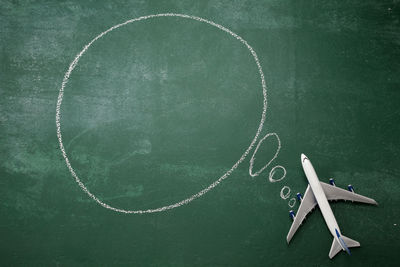 Directly above shot of blank speech bubble with toy airplane on blackboard