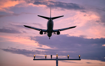 Low angle view of airplane flying against sky during sunset