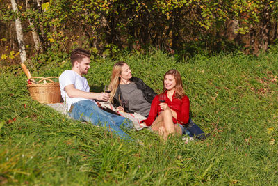 Smiling friend relaxing on grassy field