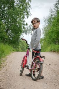 Boy standumo near bicycle on road