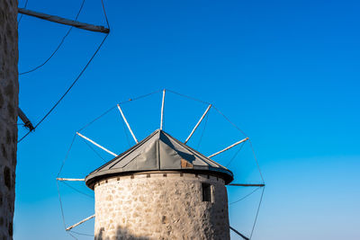 Low angle view of windmill against clear blue sky