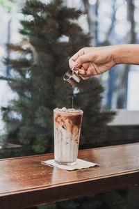 Midsection of person holding drink on table