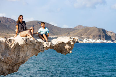 Woman and kid on a rock of playa del arco, almeria, spain