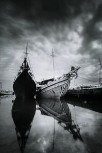 Sailboats moored on sea against sky