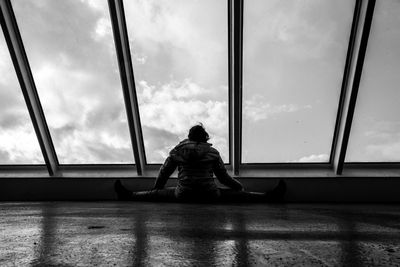 Rear view of man sitting on glass window