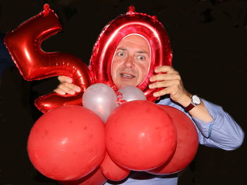 Man holding red balloons