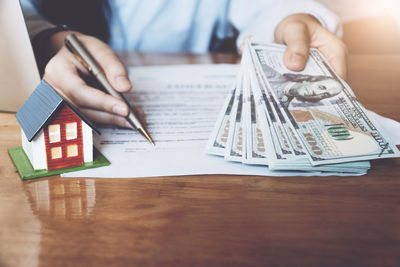 Midsection of man holding paper while sitting on table