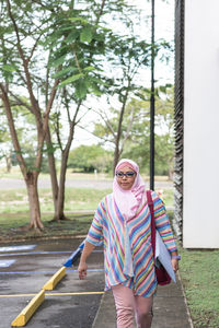 Islamic female in hijab carrying folder with documents and walking near parking lot while commuting to work in costa rica