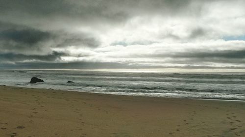 Scenic view of beach against cloudy sky