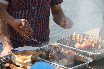 Midsection of man preparing food on barbecue grill