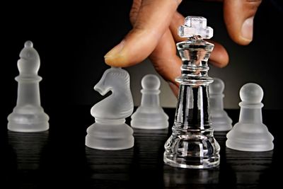 Midsection of man with chess pieces against black background