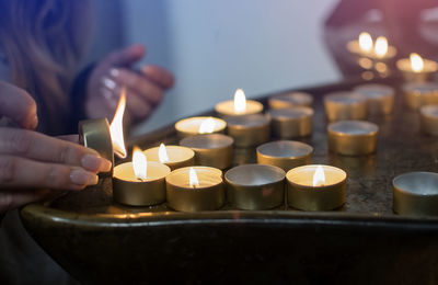 Cropped hands of woman burning tea lights on table