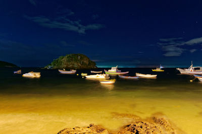 Boats moored on beach against sky at night