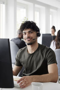 Man wearing headset using desktop pc in office