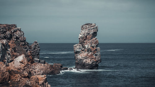 Rock formation in sea against sky