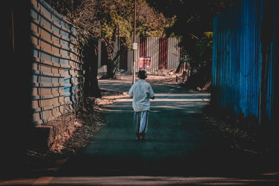 Rear view of woman walking on footpath amidst buildings