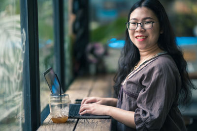 Portrait of woman with drink on table at cafe