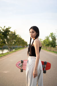 Portrait of woman standing on road against sky