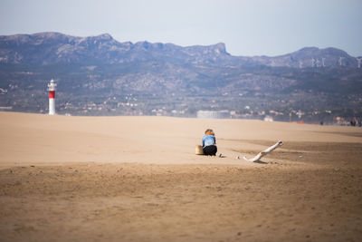 Rear view of man sitting on beach