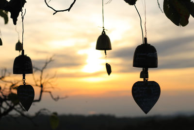 Close-up of lighting equipment hanging against sky during sunset