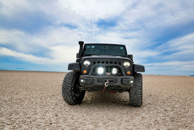 Vintage car on desert land against sky