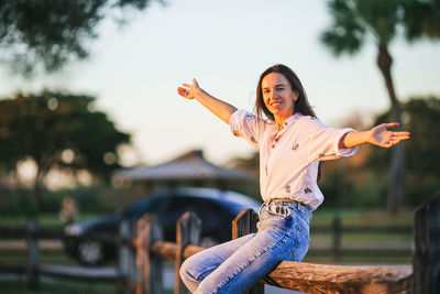 Portrait of young woman standing against railing