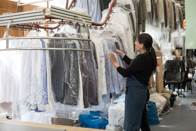 Side view of mature female dry cleaner working at laundromat