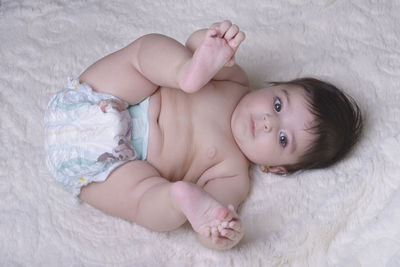 Directly above shot of shirtless baby girl lying on bed