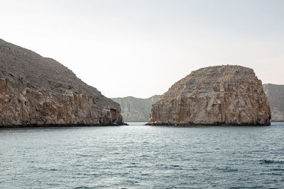 Rock formations by sea against clear sky