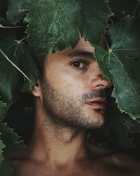 Portrait of young man with green leaves