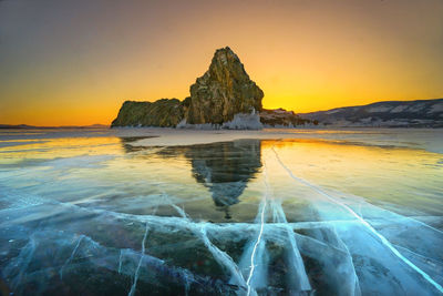 Scenic view of rock formation in sea against sky during sunset