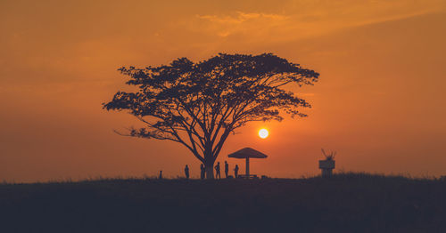 Silhouette tree on field against orange sky