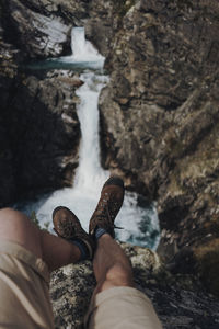 Low section of man on rock over waterfall