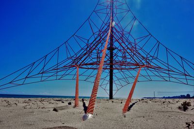 Electricity pylon on beach against clear blue sky