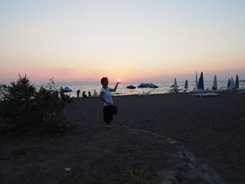 Man standing on beach against sky during sunset